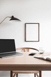 macbook on desk with white artwork on wall